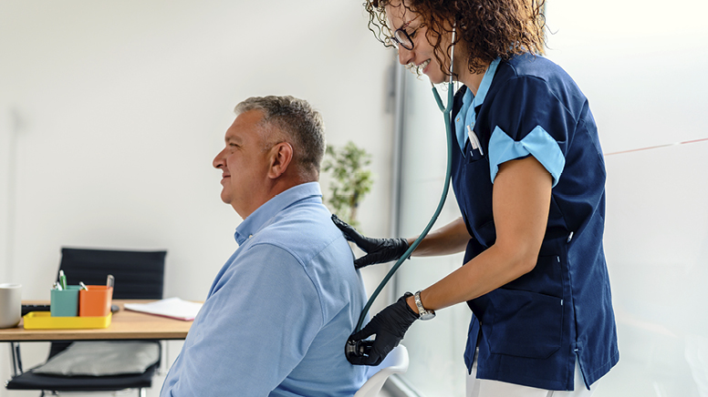 female nurse listens to lungs of older male patient