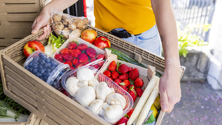 Woman holding a container of assorted fresh produce