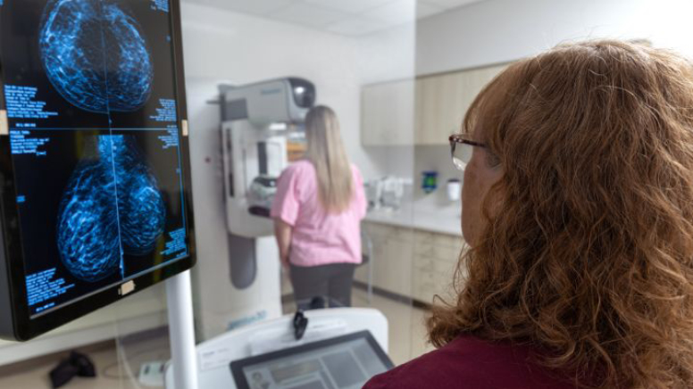 AHN technician looks at scans of patient during mammogram